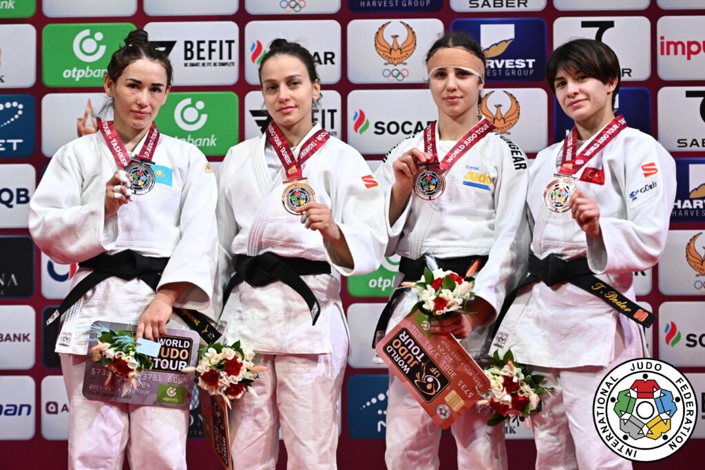 Tara i vit judodräkt står på prispallen och håller i sin bronsmedalj.