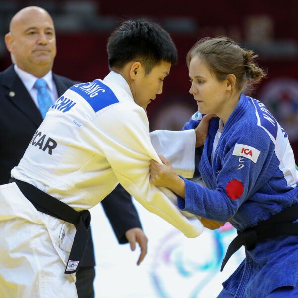 Nicolina Pernheim greppar motståndaren i en match på Grand Prix i Baku 2019. Båda står upp. I bakgrunden syns en domare.