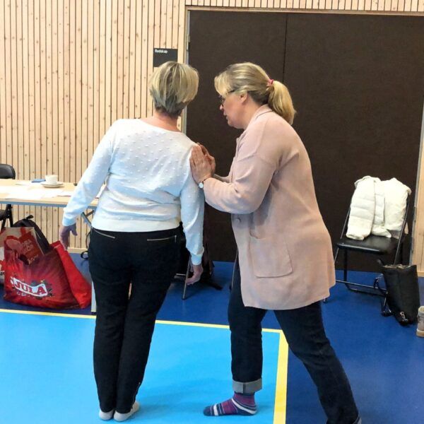 En kvinna lutar sidan av kroppen mot en annan kvinnas händer som håller emot.
