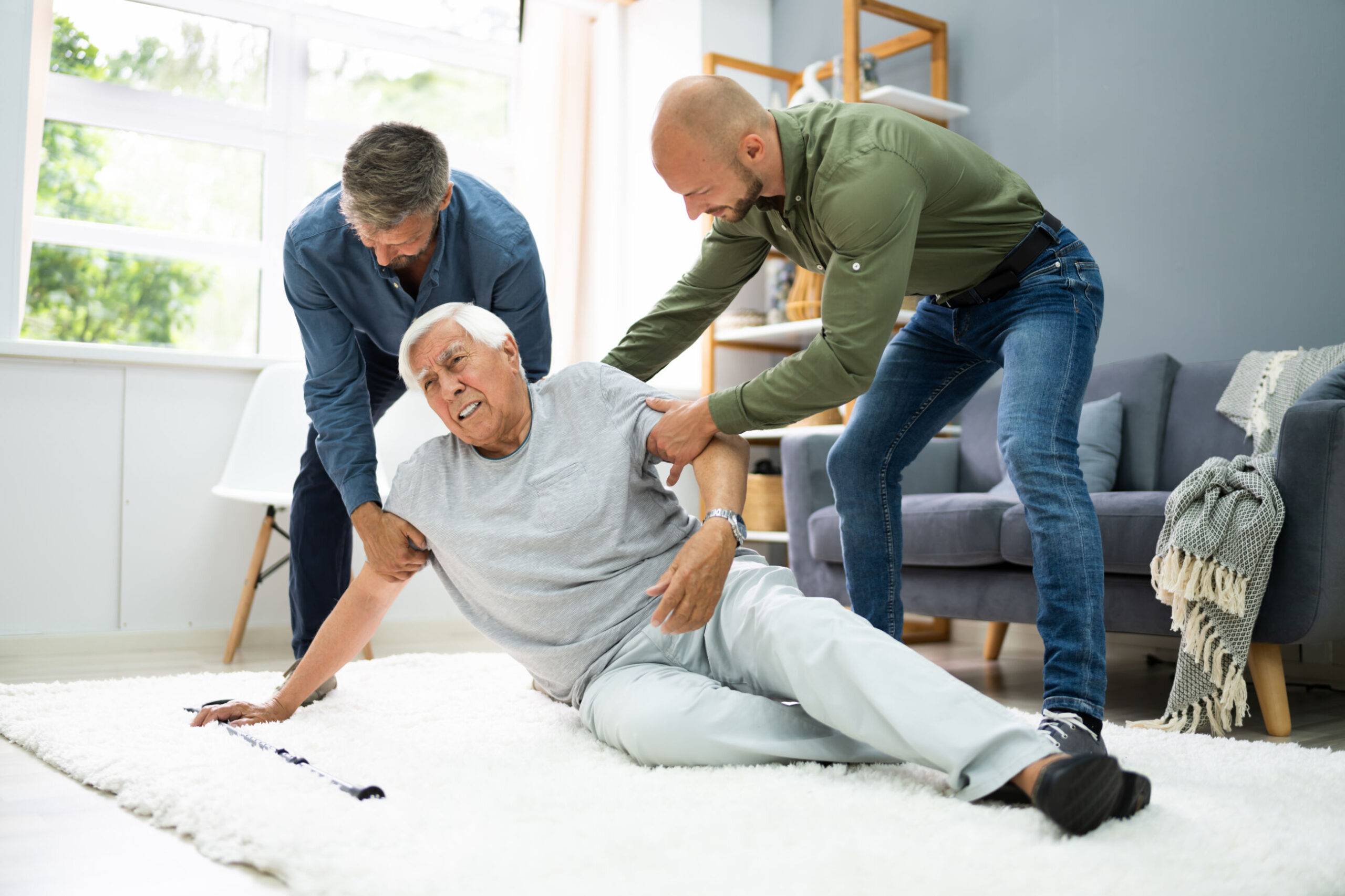 Två män hjälper en äldre man som fallit i hemmiljö.