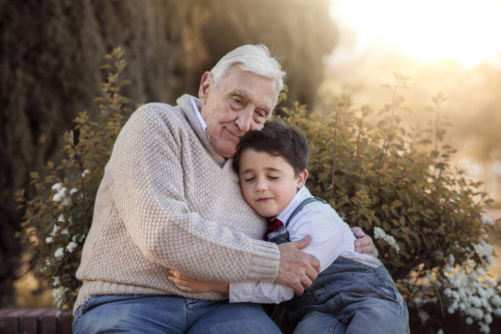 En äldre man och en pojke sitter på en bänk och kramas.