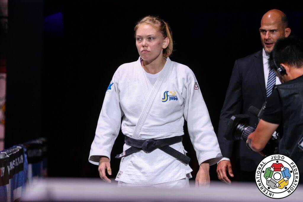 Anna Bernholm i vit judodräkt ser bestämd ut. Landslagschef Robert Eriksson går bakom.
