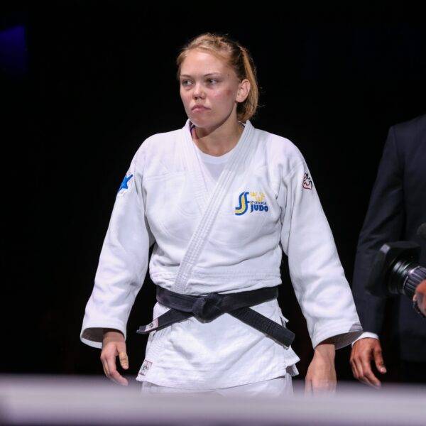 Anna Bernholm i vit judodräkt ser bestämd ut. Landslagschef Robert Eriksson går bakom.