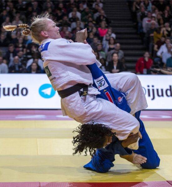 Anna Bernholm har klättrat upp på motståndare och håller dennes arm hårt, nära kroppen och lutar sig bakåt.