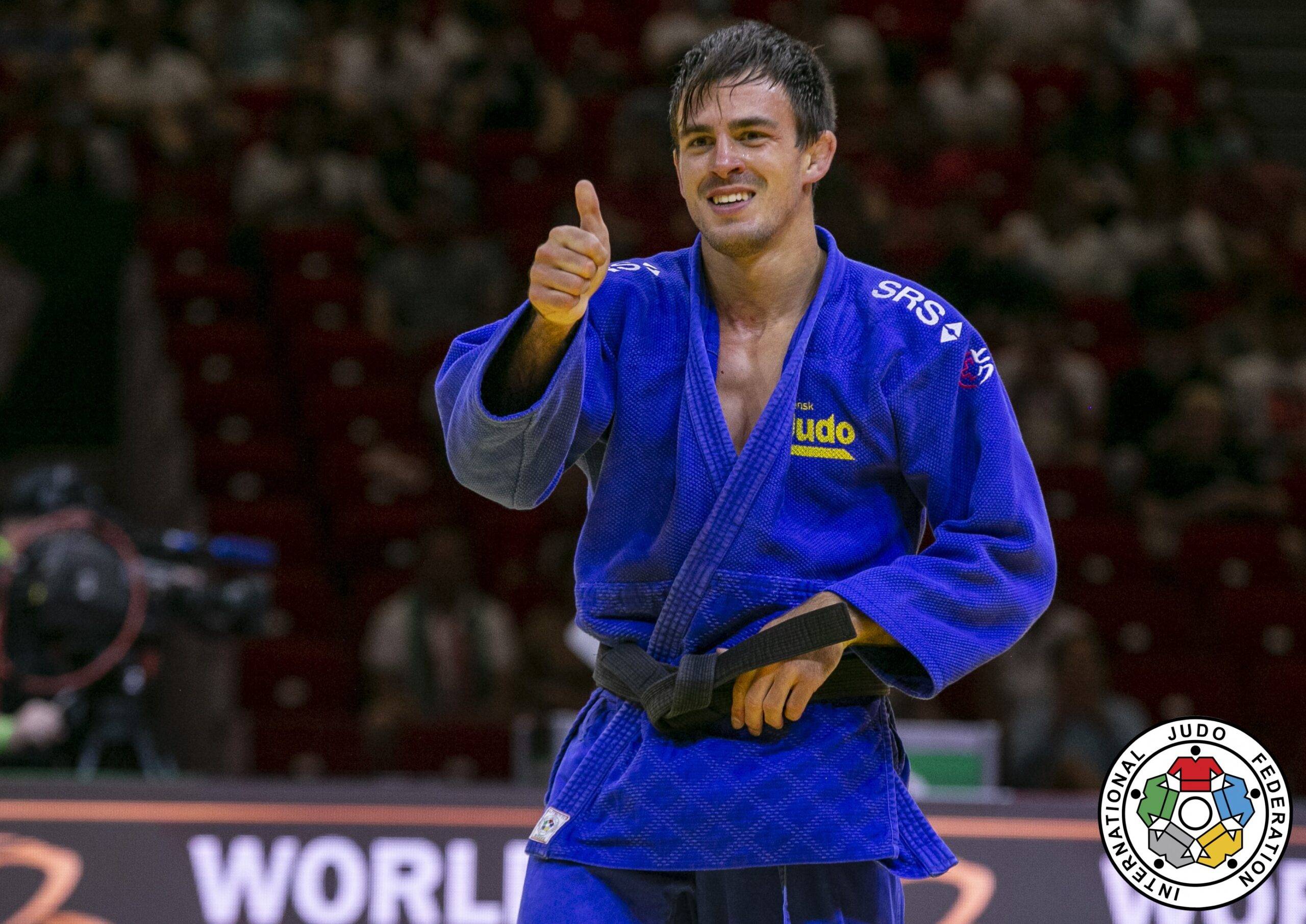 Tommy Macias i blå judodräkt ler och visar tummen upp.
