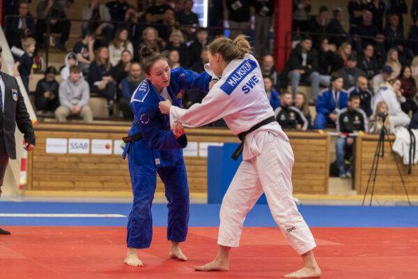 Maya Novais och Denise Malmsten står på judomattan och greppar varandra under match.