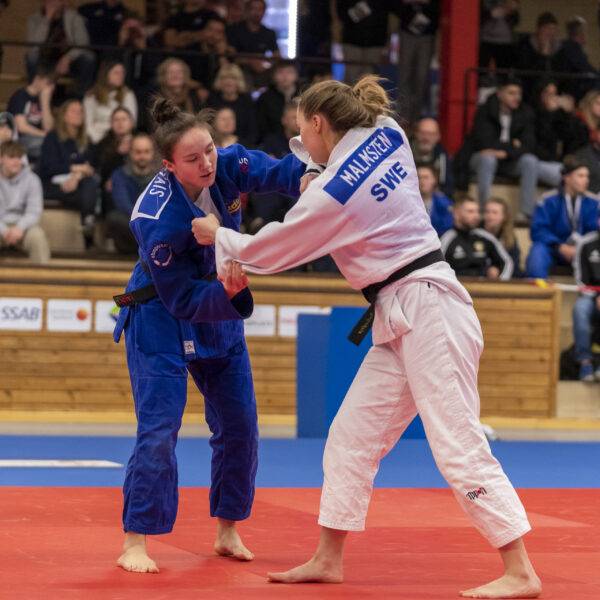 Maya Novais och Denise Malmsten står på judomattan och greppar varandra under match.