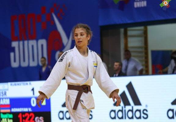 Tara Babulfath i vit judodräkt och brunt bälte går över judomattan på en tävling.