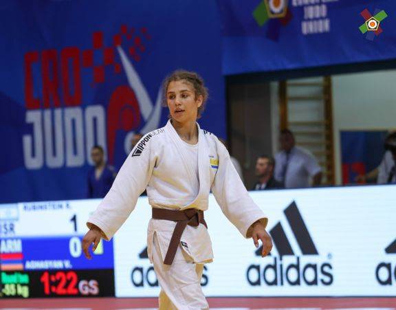 Tara Babulfath i vit judodräkt och brunt bälte går över judomattan på en tävling.