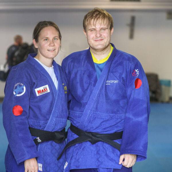 Nicolina Pernheim Goodrich och Oscar Widegren i blå judodräkter står bredvid varandra på träningsmattan.