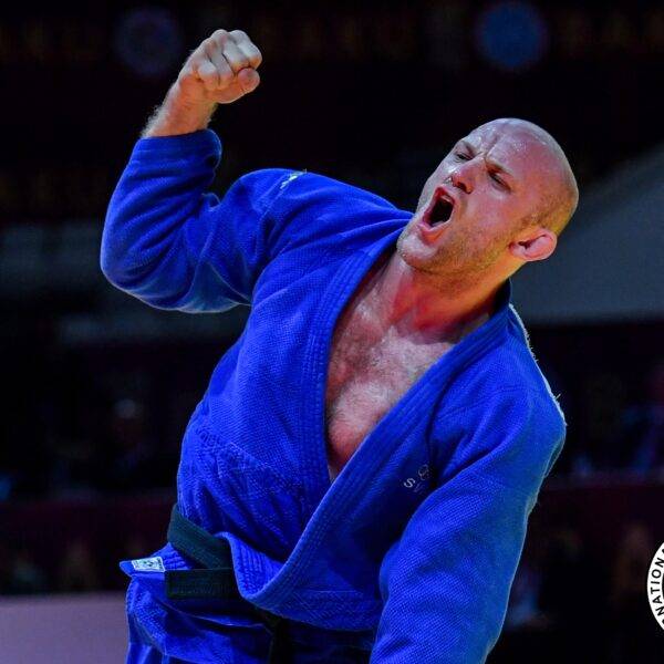 Marcus Nyman i blå judodräkt jublar och gör segergest med knuten näve.