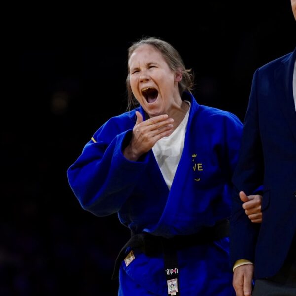 Nicolina Pernheim Goodrich i blå judodräkt gapar stort och för handen mot munnen i en gäst av stor glädje och förvåning.