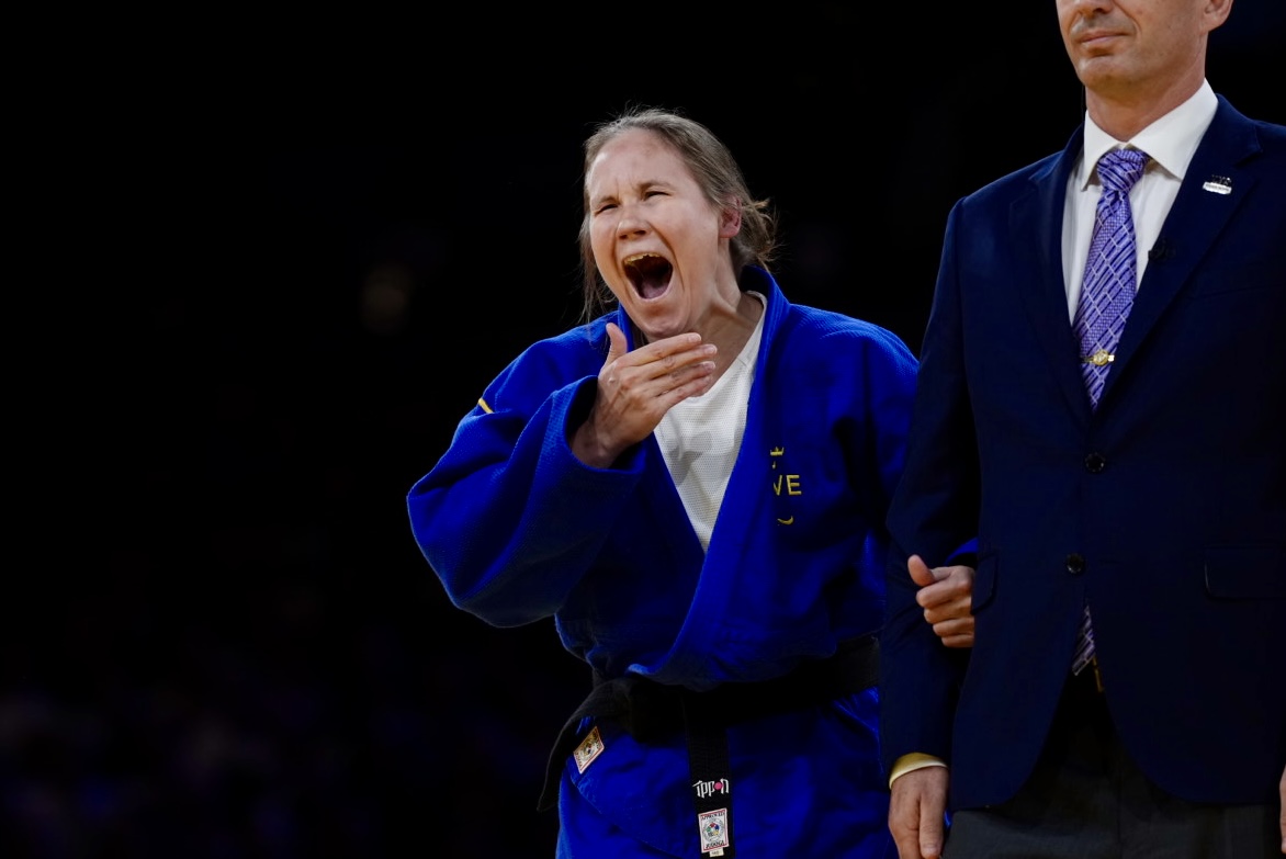 Nicolina Pernheim Goodrich i blå judodräkt gapar stort och för handen mot munnen i en gäst av stor glädje och förvåning.